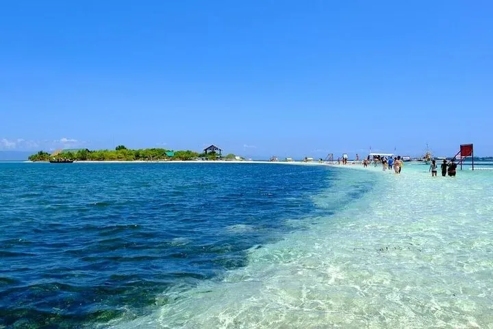 Touristen spazieren entlang einer weißen Sandbank, die aus klarem türkisfarbenem Wasser auftaucht
